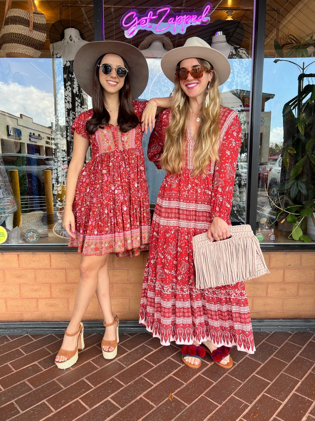 two women wearing boho style red dresses in floral print. One girl is wearing a boho mini dress and the other is wearing a boho maxi dress.