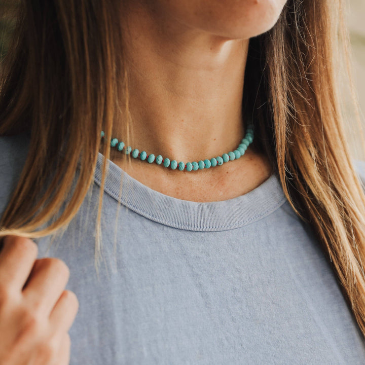 Woman wearing the turquoise gemstone necklace with a gray tee