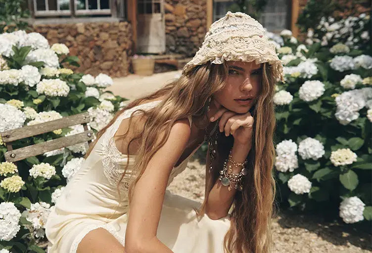 Woman in a white dress and hat sitting among white flowers