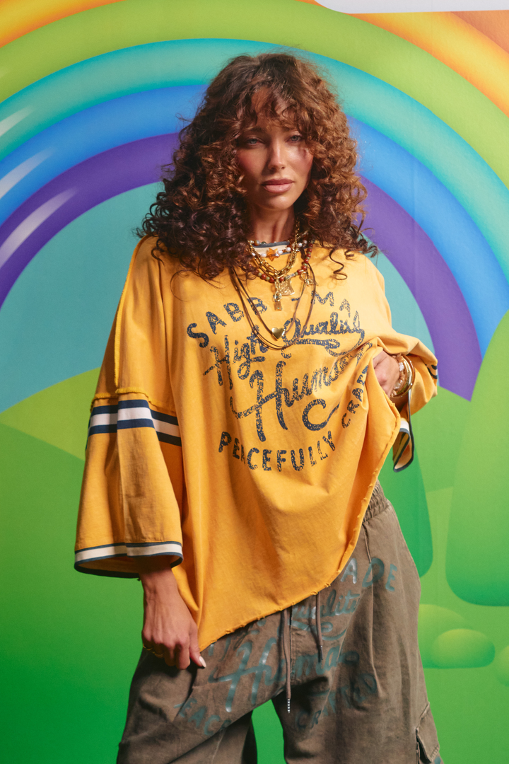 Sabbi Happy Hour tee in golden yellow, front view with High Quality Human graphic