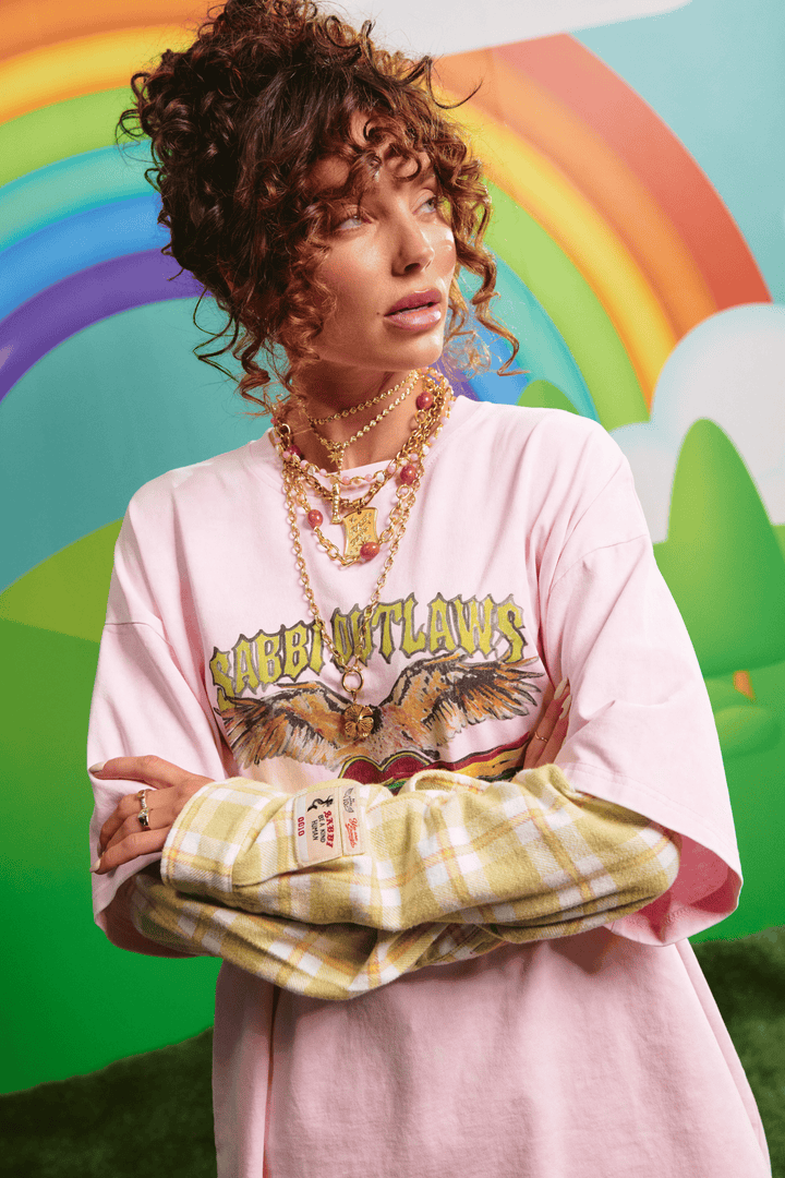 Close-up detail of the SABBI OUTLAWS graphic on the pink tee