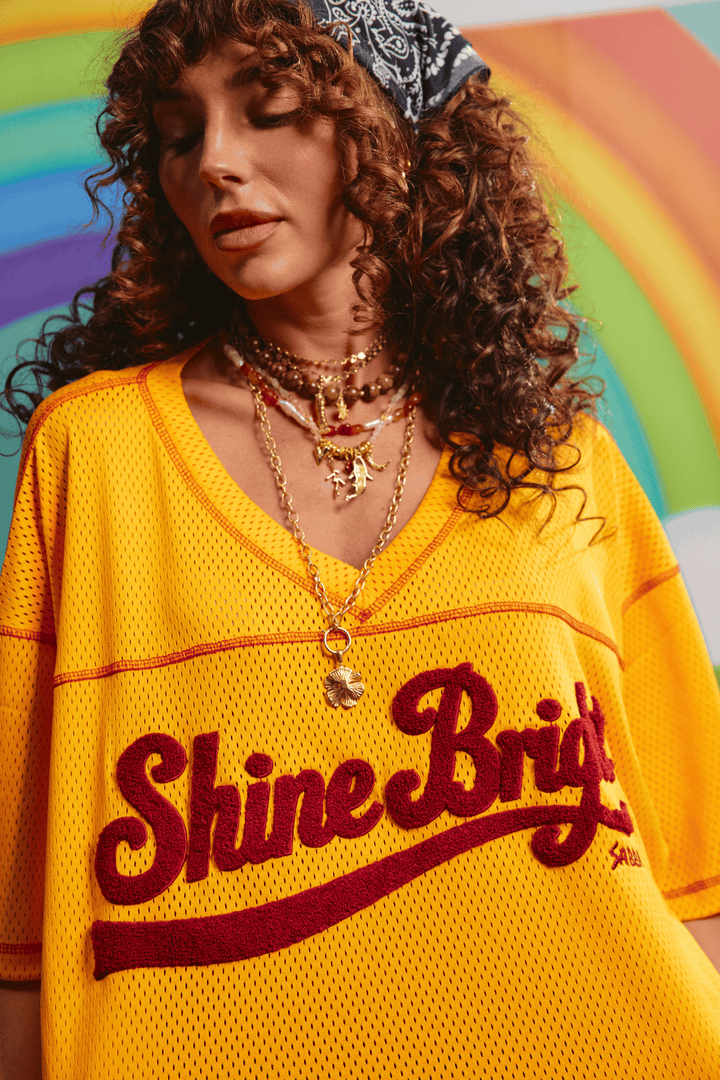 Detail of the SABBI woven hem label on the yellow mesh tee