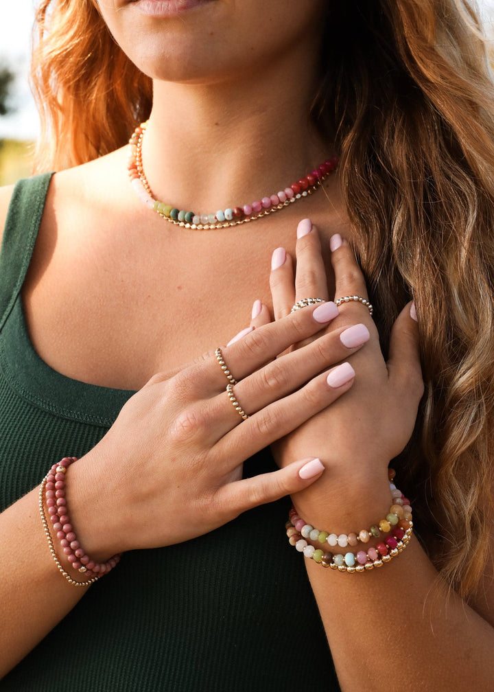 Woman wearing the Sandbar gemstone necklace with stacked bracelets
