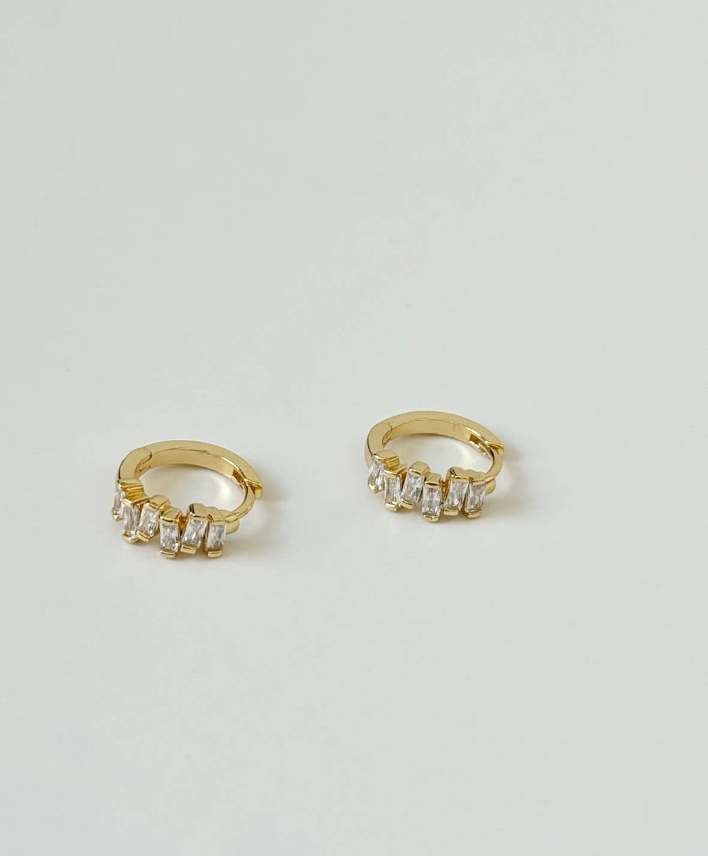 Gold hoop earrings with clear stones on a light gray background
