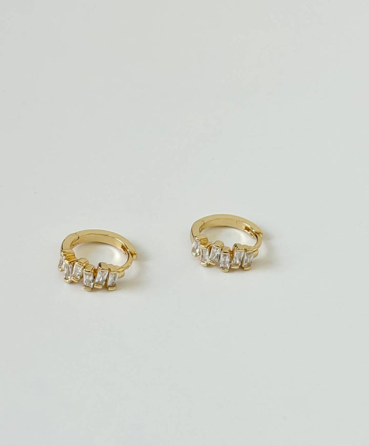 Gold hoop earrings with clear stones on a light gray background
