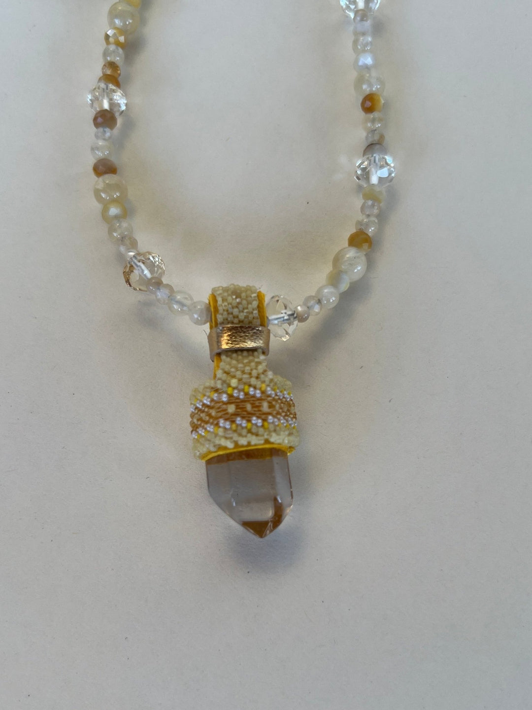 Necklace with a beaded chain and a decorative clasp on a light background