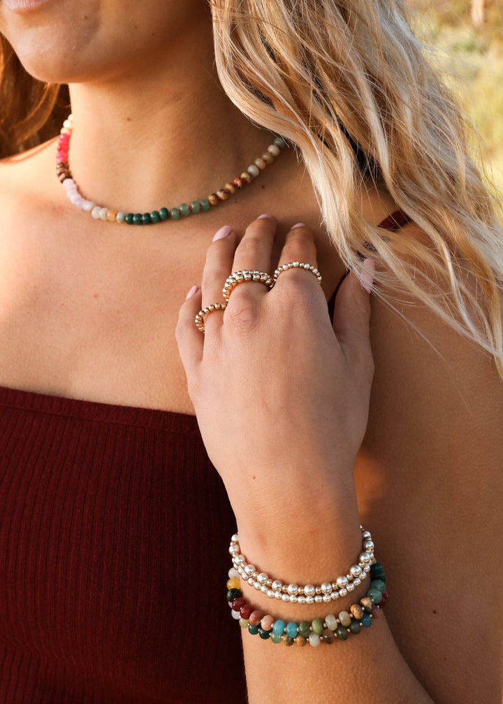 Woman wearing the Gold Rush gemstone necklace with gold rings