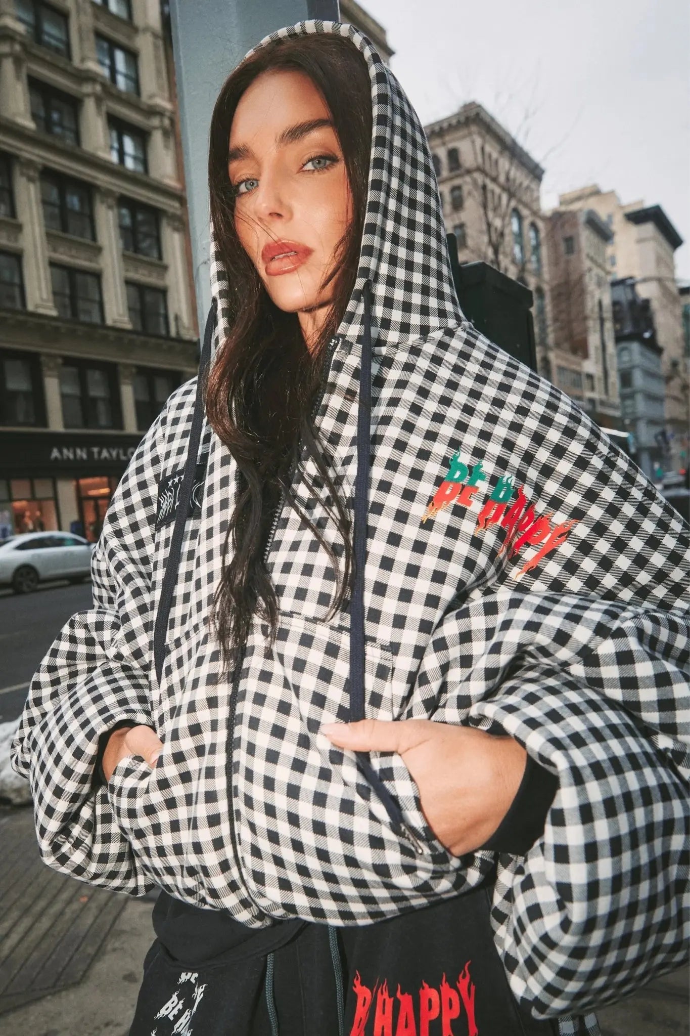 Person wearing a checkered hoodie with text in an urban setting