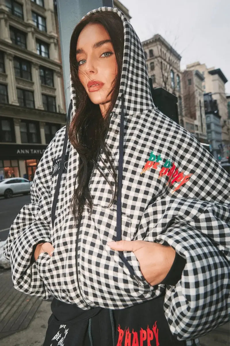 Person wearing a checkered hoodie with text on a city street