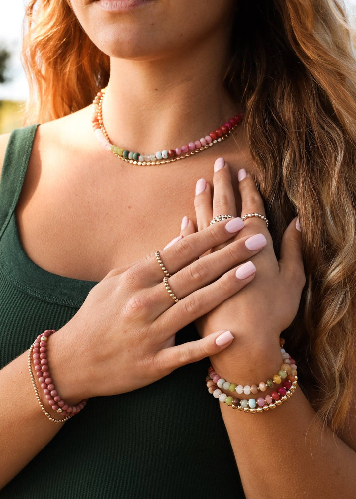 Woman wearing the Sandbar gemstone necklace with stacked bracelets