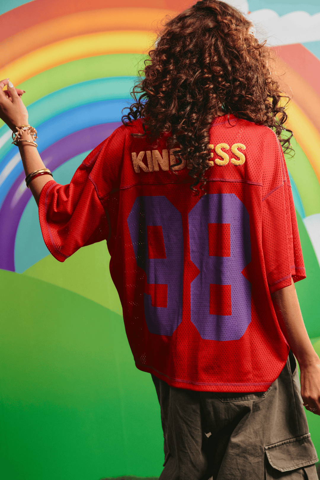 Back view of the red Sabbi Shine Bright mesh tee showing the KINDNESS graphic