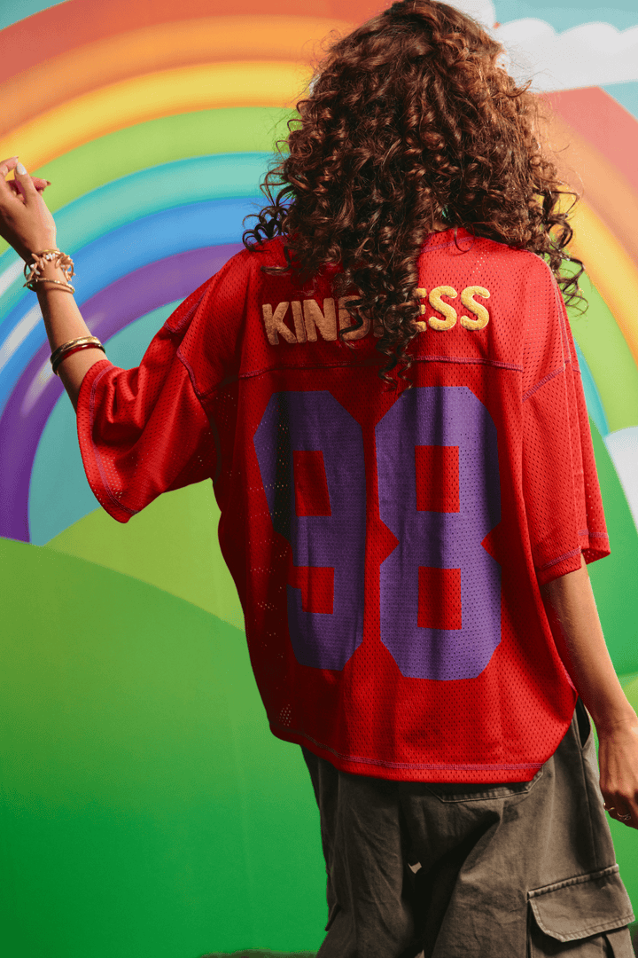 Back view of the red Sabbi Shine Bright mesh tee showing the KINDNESS graphic
