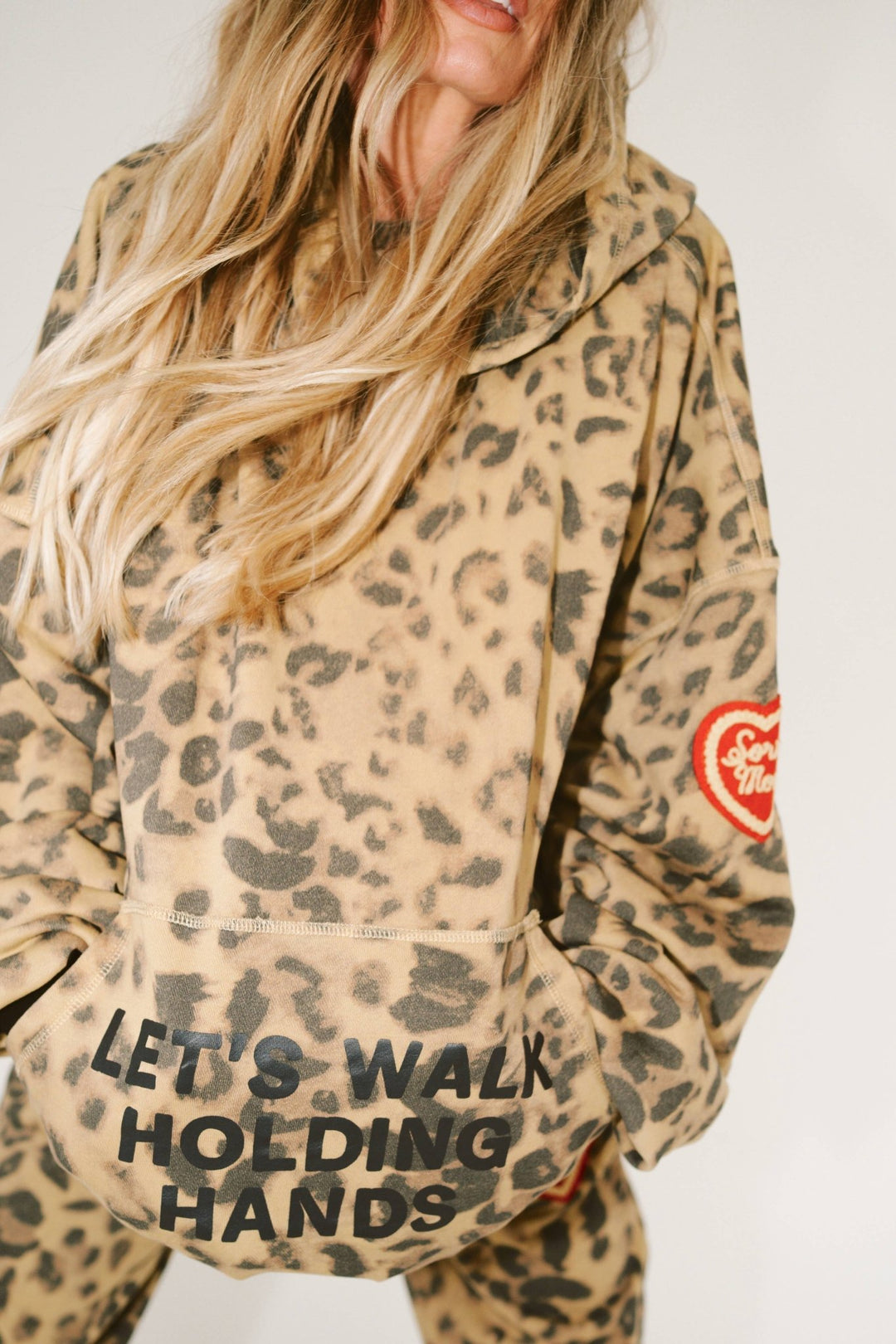 Person wearing a leopard print jacket with text and a heart logo on a white background